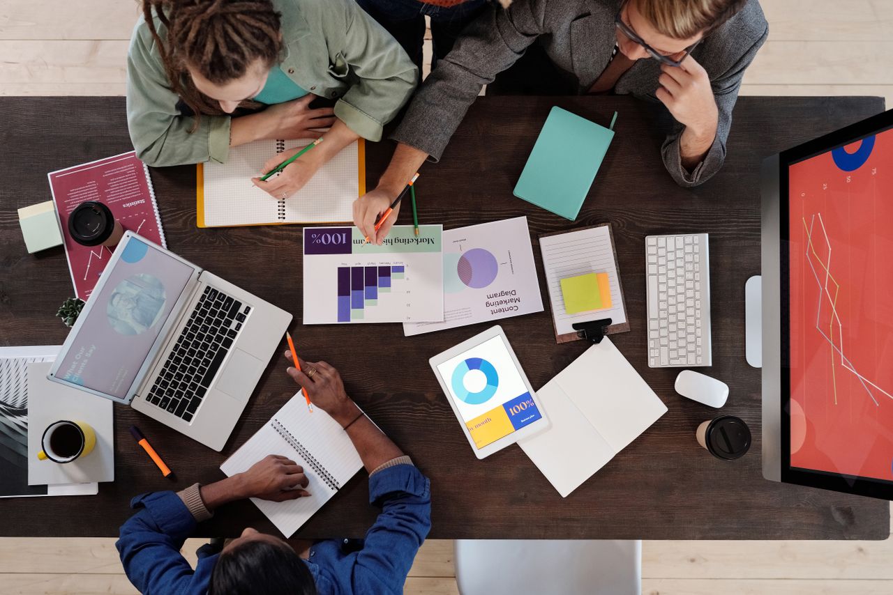 Vue plongeante d’une équipe diversifiée travaillant ensemble sur un projet dans un bureau moderne.
